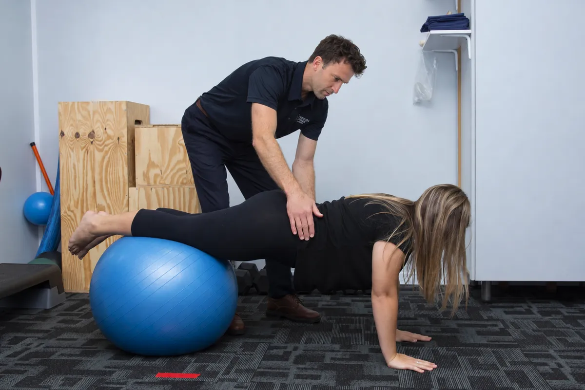 Biokineticist guiding a client's exercise technique in a biokinetics practice